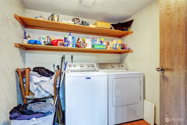 clothes washing area with washing machine and clothes dryer and a textured ceiling