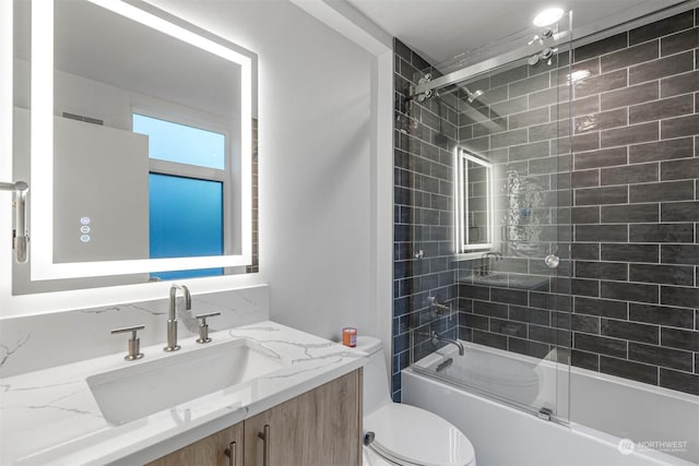 full bathroom featuring vanity, enclosed tub / shower combo, and toilet