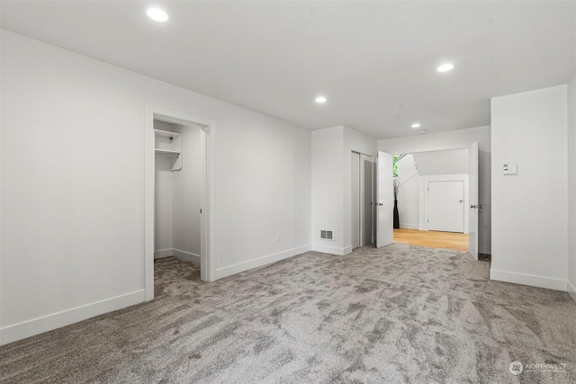 unfurnished bedroom featuring a walk in closet and carpet