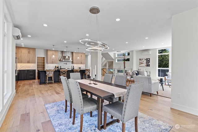 dining space with a wall mounted air conditioner, an inviting chandelier, and light hardwood / wood-style flooring