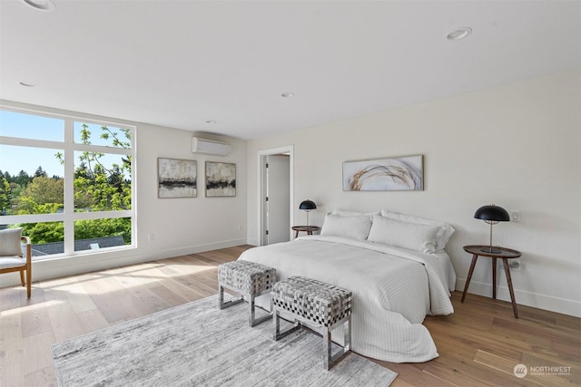 bedroom with a wall mounted air conditioner and hardwood / wood-style floors