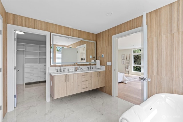 bathroom with a bath, vanity, and wood walls