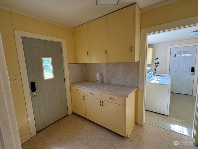 kitchen with washer and clothes dryer, decorative backsplash, and cream cabinetry