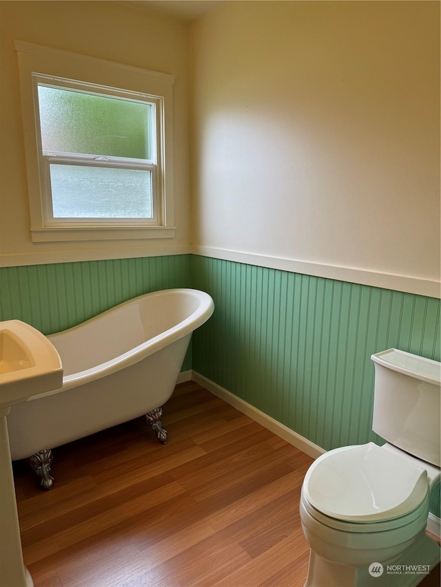 bathroom with wood-type flooring, toilet, and a bathing tub