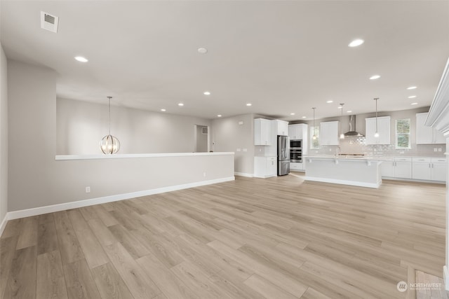 unfurnished living room featuring light wood-type flooring and an inviting chandelier