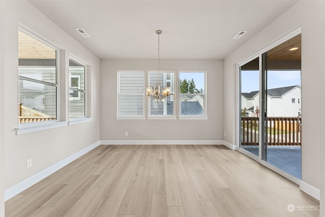 unfurnished dining area featuring light hardwood / wood-style floors and a chandelier