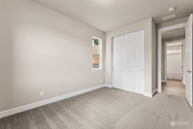 unfurnished bedroom with a closet and light colored carpet