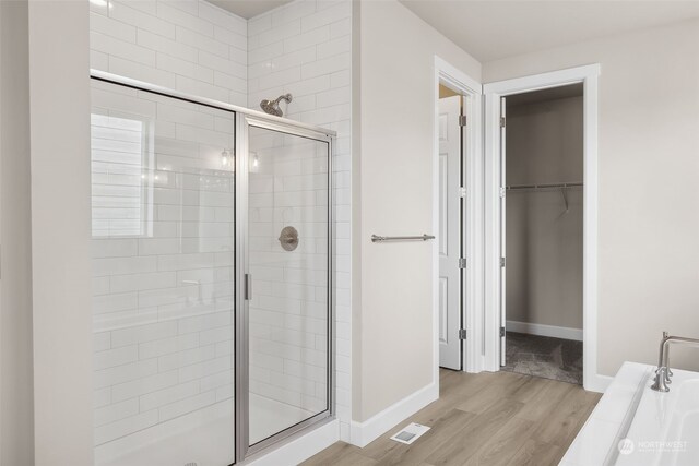 bathroom with hardwood / wood-style floors and independent shower and bath