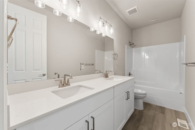 full bathroom featuring vanity, hardwood / wood-style flooring, shower / tub combination, and toilet