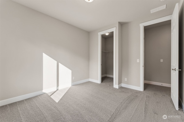 unfurnished bedroom featuring light carpet, a closet, and a walk in closet