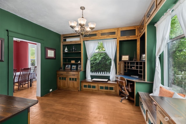 interior space featuring an inviting chandelier, hardwood / wood-style flooring, a wealth of natural light, and built in desk