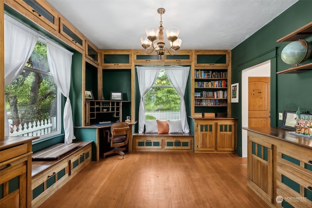 sitting room with built in features, a chandelier, and light hardwood / wood-style floors