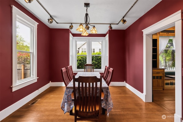 dining room with a notable chandelier, hardwood / wood-style flooring, and rail lighting