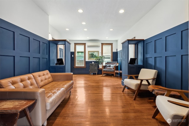 living room with a wall mounted air conditioner and wood-type flooring