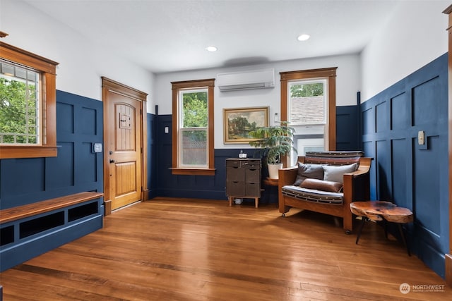 living area featuring hardwood / wood-style flooring, a healthy amount of sunlight, and a wall mounted AC