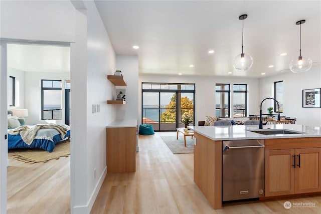 kitchen with sink, light hardwood / wood-style flooring, hanging light fixtures, a center island with sink, and stainless steel dishwasher