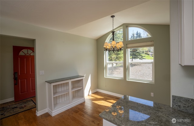 unfurnished dining area featuring a chandelier, lofted ceiling, and wood-type flooring