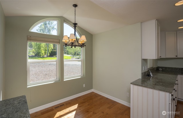 kitchen featuring decorative light fixtures, an inviting chandelier, white cabinetry, wood-type flooring, and lofted ceiling