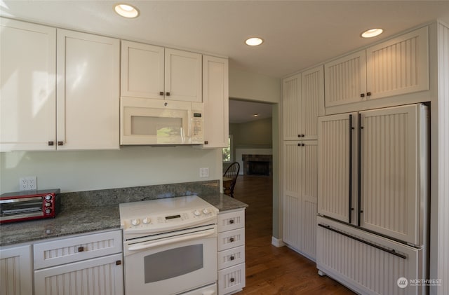 kitchen featuring white appliances, dark stone counters, and dark hardwood / wood-style flooring