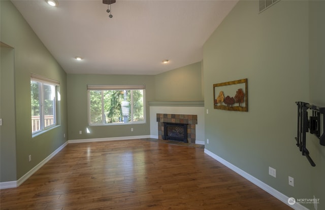 unfurnished living room featuring high vaulted ceiling, dark hardwood / wood-style flooring, and a tile fireplace