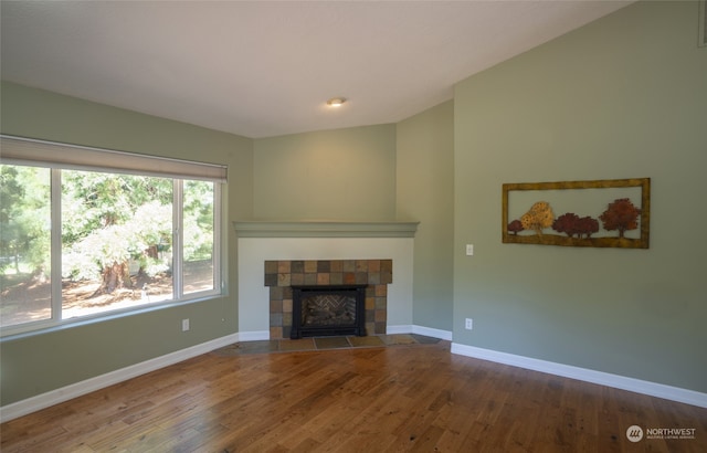 unfurnished living room featuring wood-type flooring and a tile fireplace