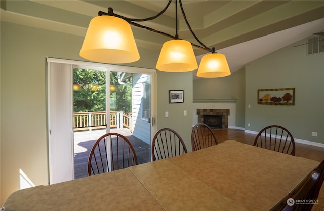 dining area featuring a tiled fireplace, lofted ceiling, and dark hardwood / wood-style flooring