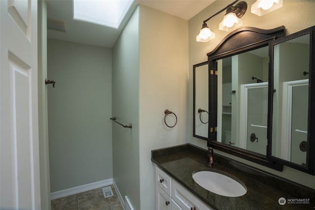 bathroom featuring tile flooring, vanity, and a skylight