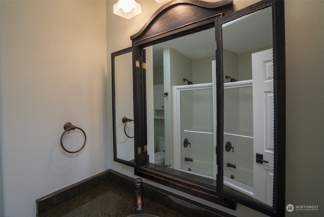 bathroom featuring bath / shower combo with glass door and toilet