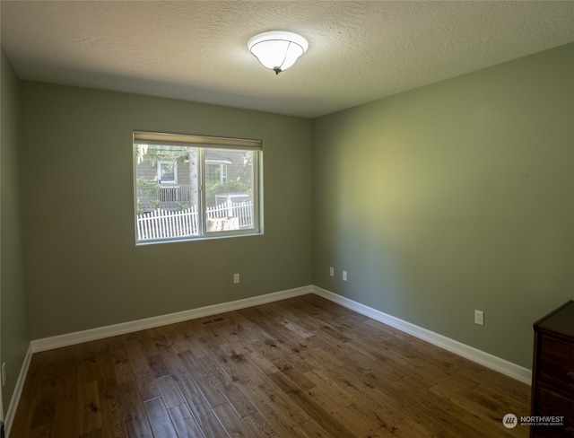 unfurnished room with hardwood / wood-style flooring and a textured ceiling