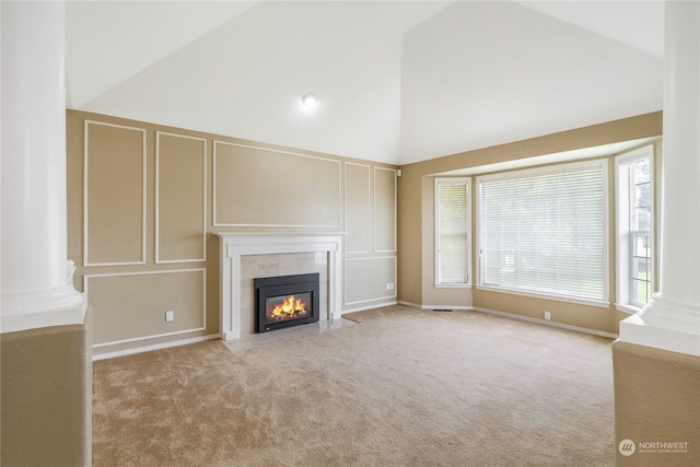 unfurnished living room with light carpet, high vaulted ceiling, and a tile fireplace