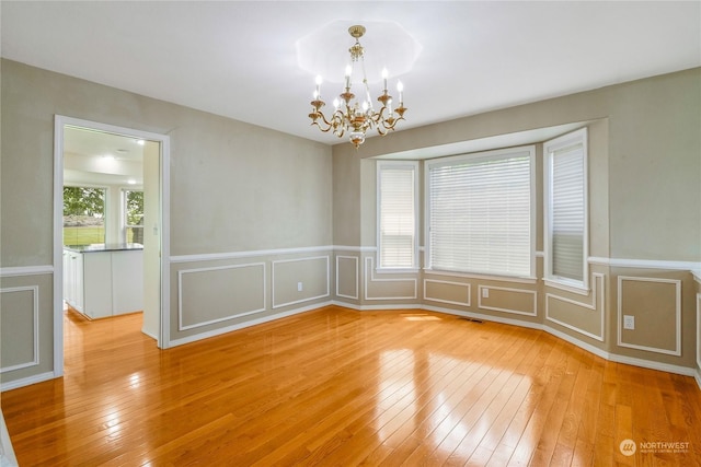 unfurnished room featuring light wood-type flooring and a notable chandelier