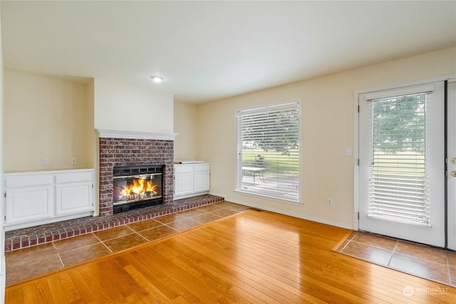 unfurnished living room featuring hardwood / wood-style flooring and a brick fireplace