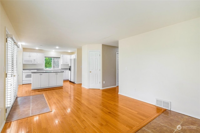 kitchen with white cabinets, white appliances, light hardwood / wood-style flooring, and sink