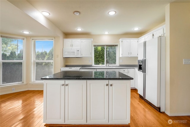 kitchen with white cabinets, a center island, white appliances, and light hardwood / wood-style flooring