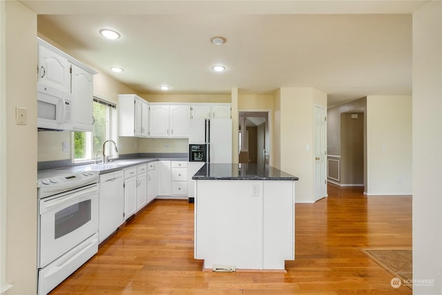 kitchen with white appliances, dark stone countertops, white cabinets, light hardwood / wood-style floors, and a kitchen island