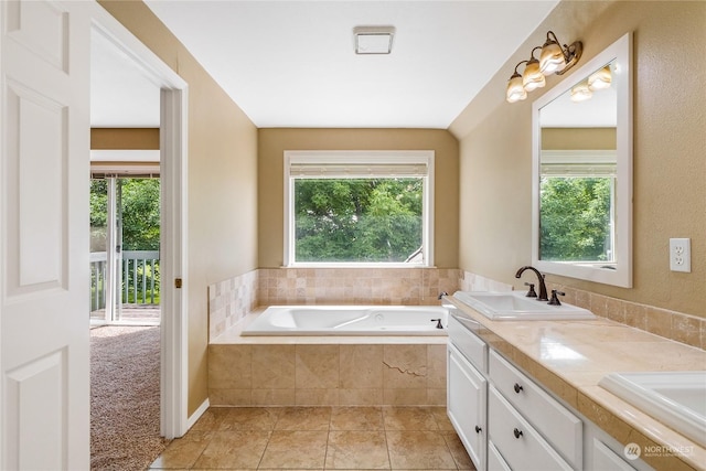 bathroom featuring tile patterned floors, a wealth of natural light, vanity, and a relaxing tiled tub