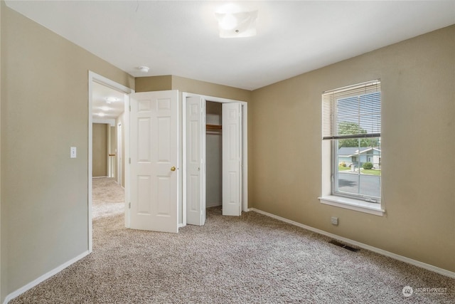 unfurnished bedroom with light colored carpet and a closet