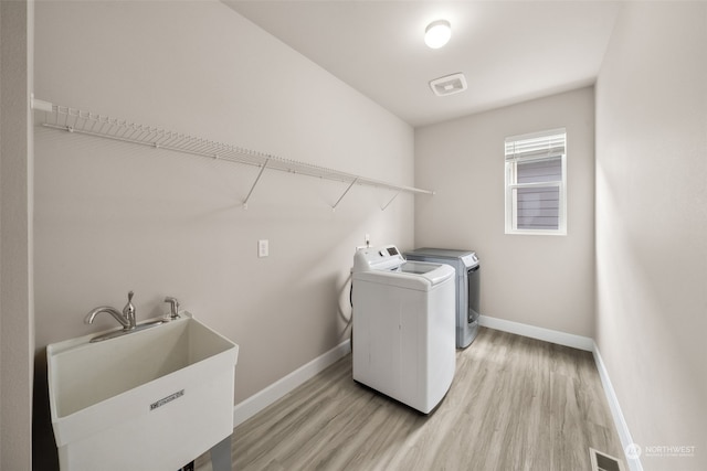 washroom with sink, washer and clothes dryer, and light wood-type flooring