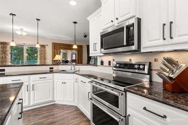 kitchen with white cabinets, appliances with stainless steel finishes, hanging light fixtures, and sink