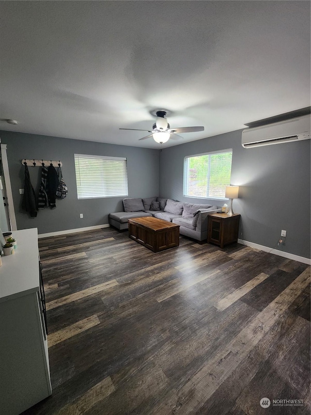 unfurnished living room with a wall mounted air conditioner, baseboards, and dark wood-style flooring