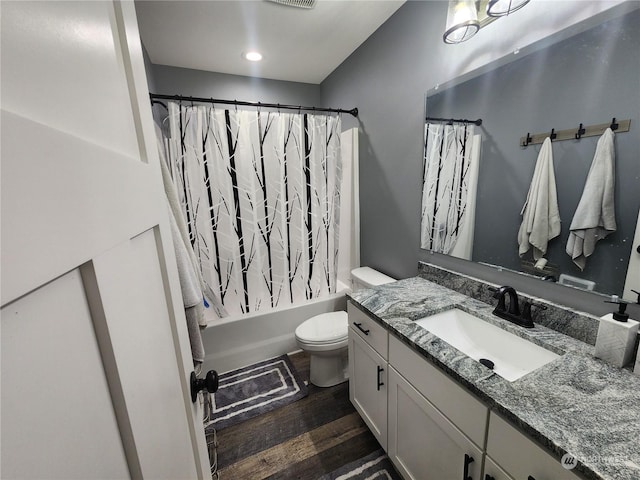 bathroom featuring visible vents, toilet, shower / tub combo, wood finished floors, and vanity