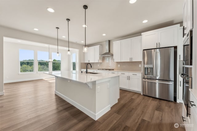 kitchen featuring hanging light fixtures, stainless steel appliances, wall chimney range hood, and dark hardwood / wood-style flooring