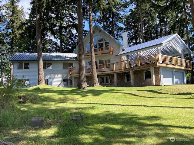 rear view of property with a garage, a wooden deck, and a lawn