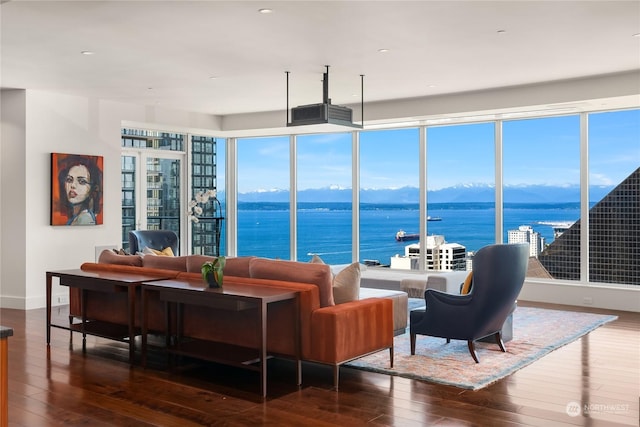 living room with dark wood-type flooring, a healthy amount of sunlight, and a water and mountain view