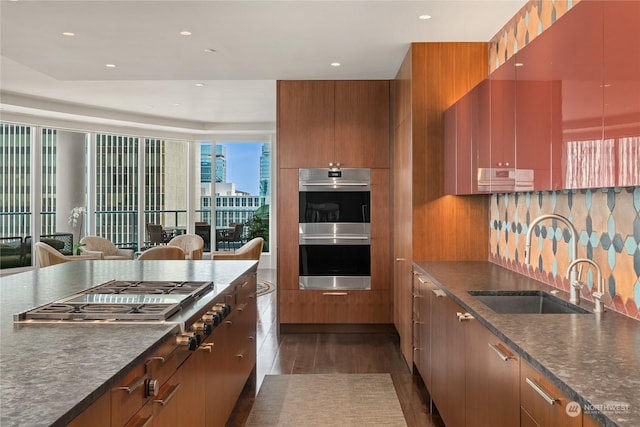 kitchen with stainless steel appliances, sink, dark wood-type flooring, and backsplash