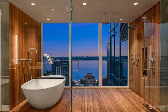 bathroom with hardwood / wood-style flooring, wood walls, a water view, and independent shower and bath