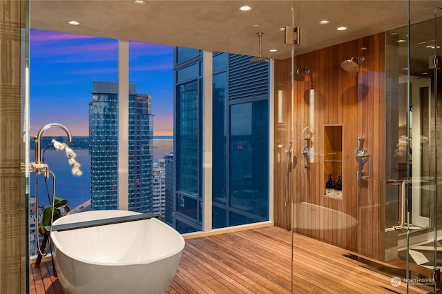 bathroom featuring wood walls, hardwood / wood-style floors, and a washtub