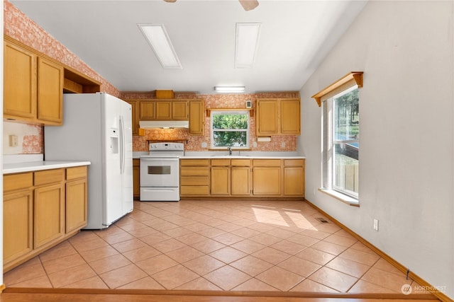 kitchen with sink, white appliances, vaulted ceiling, and light tile patterned flooring