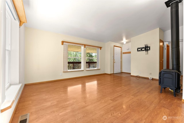 unfurnished living room with light wood-type flooring and a wood stove