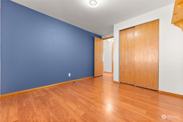 unfurnished bedroom with wood-type flooring and a closet